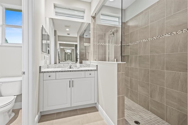 bathroom featuring a tile shower, vanity, tile patterned floors, and toilet