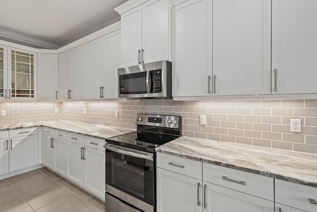 kitchen featuring light stone counters, appliances with stainless steel finishes, light tile patterned floors, white cabinets, and decorative backsplash