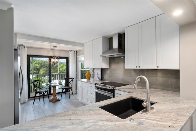 kitchen featuring wall chimney range hood, white cabinetry, sink, and appliances with stainless steel finishes