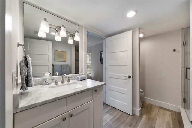 bathroom featuring hardwood / wood-style floors, vanity, toilet, and an enclosed shower