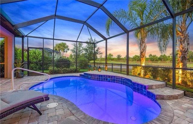 pool at dusk with glass enclosure, a patio area, and an outdoor pool