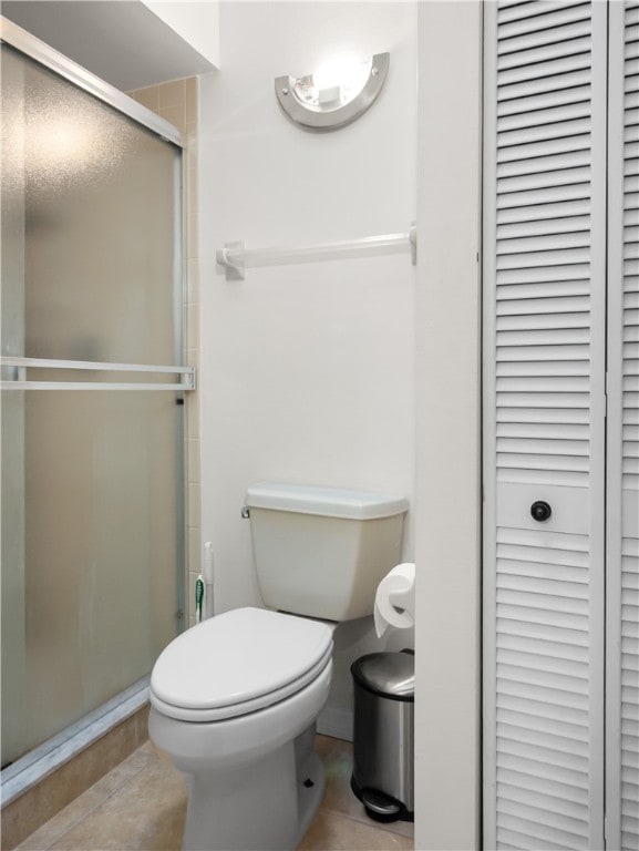 bathroom with toilet, tile patterned floors, and a shower with shower door