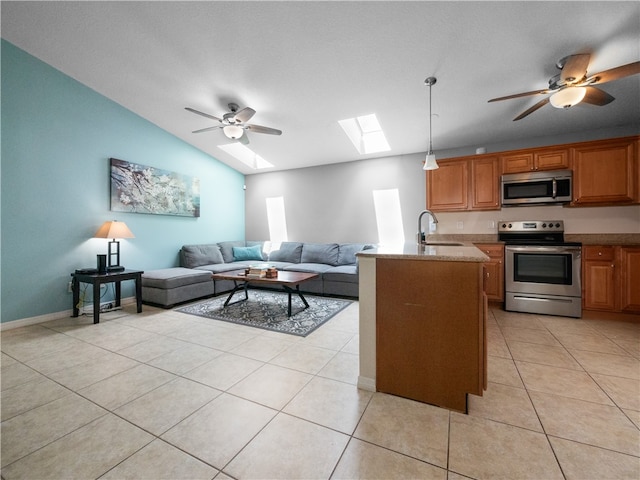 kitchen with light tile patterned floors, ceiling fan, lofted ceiling with skylight, appliances with stainless steel finishes, and decorative light fixtures