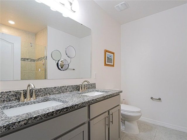 bathroom with toilet, double vanity, a sink, and tile patterned floors