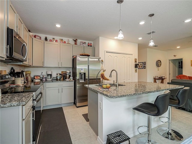 kitchen with stone countertops, appliances with stainless steel finishes, a breakfast bar area, and recessed lighting