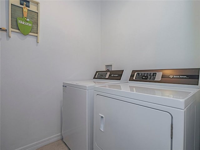 laundry room with laundry area, washing machine and dryer, baseboards, and light tile patterned flooring