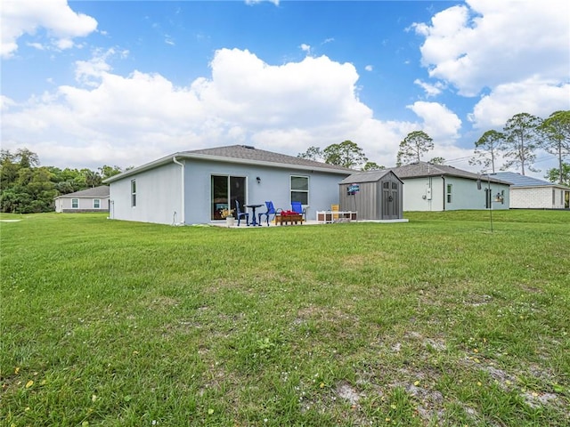 back of property featuring a yard, an outdoor structure, a storage shed, and a patio