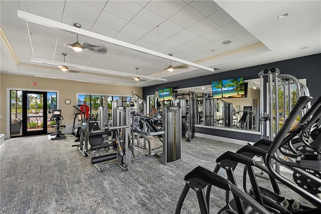 workout area with french doors, a raised ceiling, and carpet