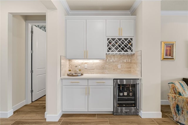 bar with white cabinetry, beverage cooler, and crown molding