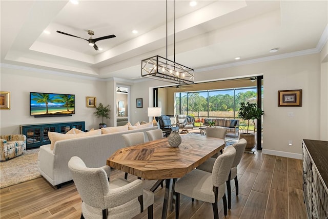 dining space with hardwood / wood-style floors, a raised ceiling, and ceiling fan