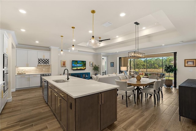 kitchen featuring stainless steel appliances, a raised ceiling, sink, and white cabinets