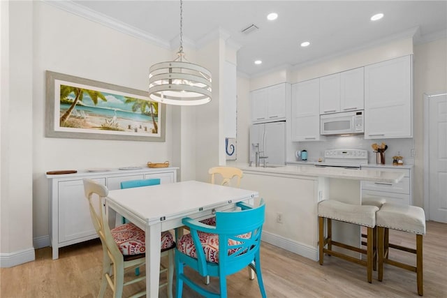 dining space featuring visible vents, light wood-style floors, and ornamental molding