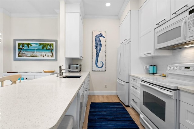 kitchen with light wood finished floors, light stone countertops, ornamental molding, white appliances, and a sink