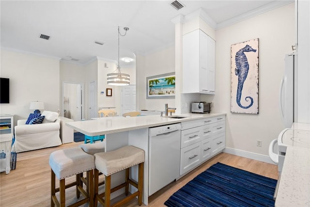 kitchen with a sink, visible vents, white appliances, and a peninsula