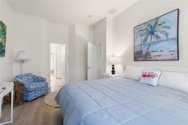 bedroom featuring visible vents, ensuite bath, and wood finished floors