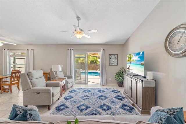 living room featuring vaulted ceiling, light tile patterned floors, a ceiling fan, and a textured ceiling