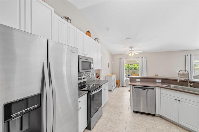 kitchen with a sink, tasteful backsplash, stainless steel appliances, white cabinets, and ceiling fan