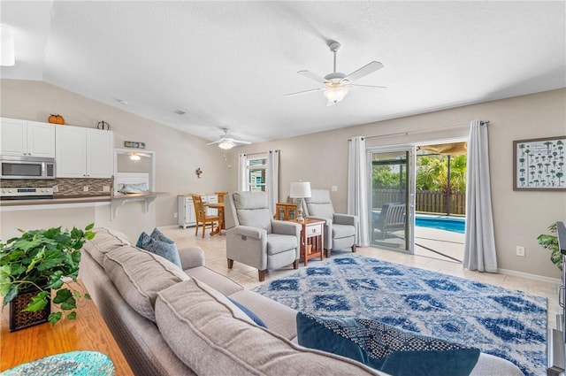 living room with light tile patterned floors, ceiling fan, baseboards, and lofted ceiling