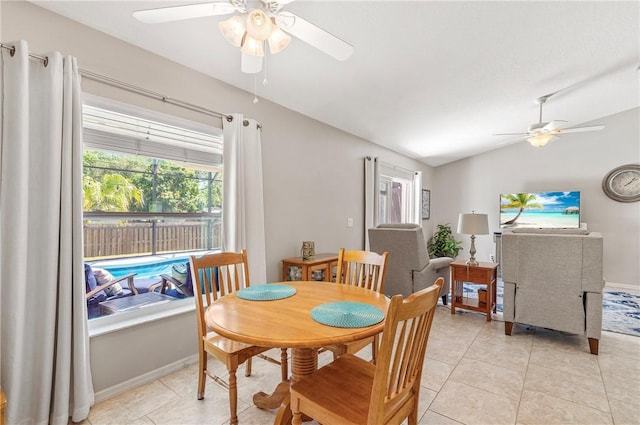 dining area with light tile patterned flooring, baseboards, a ceiling fan, and vaulted ceiling