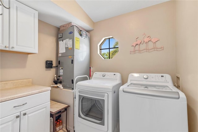 laundry area featuring washing machine and dryer, heating unit, and cabinet space