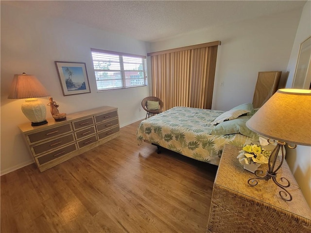 28 Pine Arbor Ln Unit 202, Vero Beach, FL 32962 - bedroom with a textured ceiling, wood finished floors, and baseboards