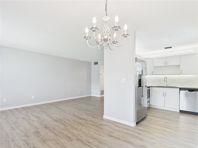 96 Spring Lake Dr Unit 105, Vero Beach, FL 32962 - kitchen featuring a chandelier, appliances with stainless steel finishes, light wood-style flooring, backsplash, and open floor plan