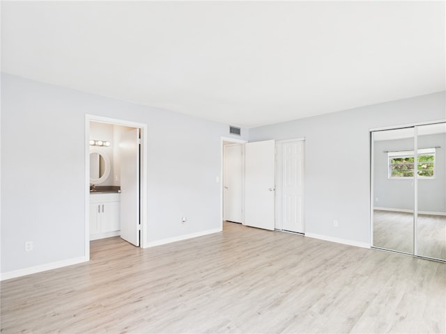 96 Spring Lake Dr Unit 105, Vero Beach, FL 32962 - unfurnished bedroom with two closets, light wood-style floors, and ensuite bath