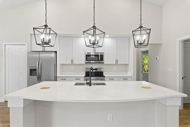 kitchen featuring appliances with stainless steel finishes, a kitchen island with sink, and hanging light fixtures