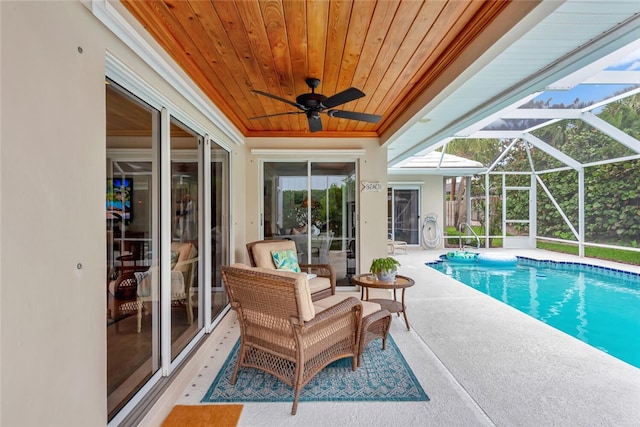 pool with glass enclosure, ceiling fan, and a patio