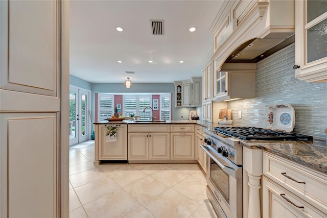 kitchen featuring cream cabinets, high end stove, glass insert cabinets, and custom range hood