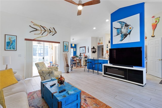 living room with ceiling fan, vaulted ceiling, and light wood-type flooring