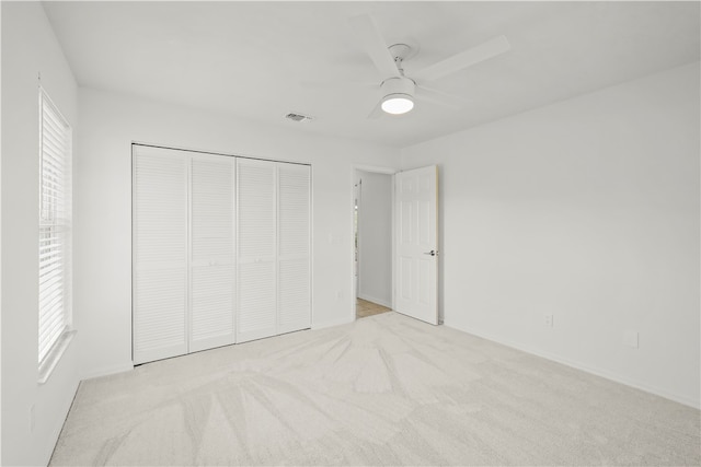 unfurnished bedroom featuring ceiling fan, light carpet, and a closet