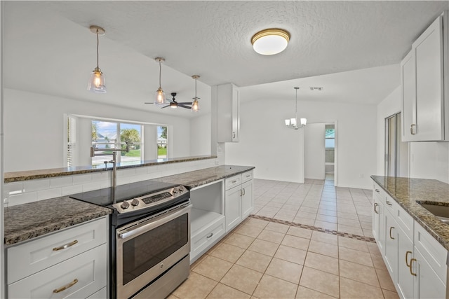 kitchen with dark stone countertops, stainless steel electric range, lofted ceiling, and white cabinets