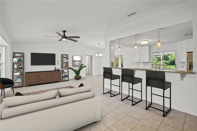 tiled living room featuring ceiling fan with notable chandelier and vaulted ceiling