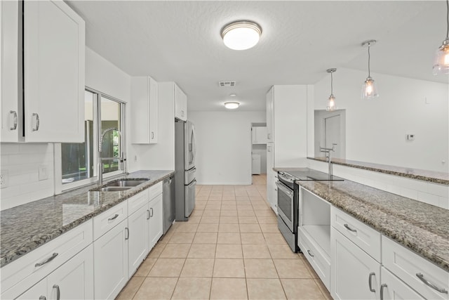 kitchen with dark stone counters, appliances with stainless steel finishes, vaulted ceiling, and white cabinets