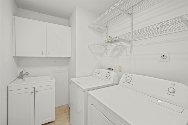 laundry room with cabinets, light tile patterned floors, sink, and washing machine and clothes dryer