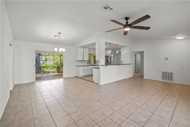 unfurnished living room with lofted ceiling, light tile patterned floors, and ceiling fan with notable chandelier