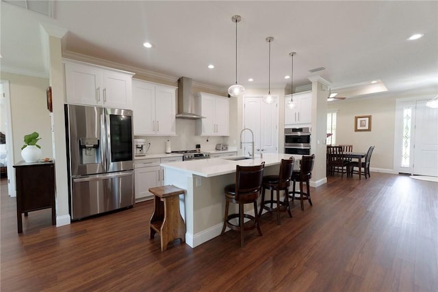 kitchen featuring appliances with stainless steel finishes, wall chimney exhaust hood, a sink, dark wood-style floors, and ornamental molding
