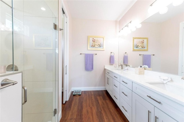 bathroom featuring double vanity, baseboards, wood finished floors, and a shower stall