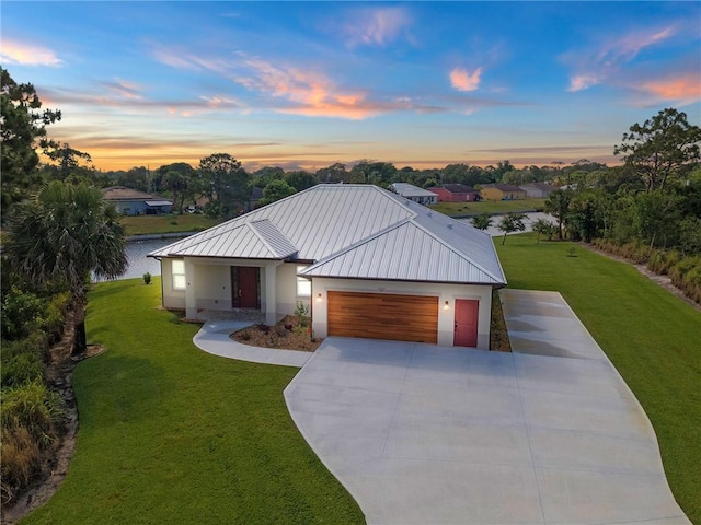 view of front of property with a front lawn, an attached garage, a standing seam roof, and metal roof