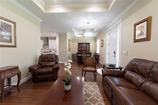 living room featuring a raised ceiling, dark wood-style floors, a chandelier, crown molding, and baseboards