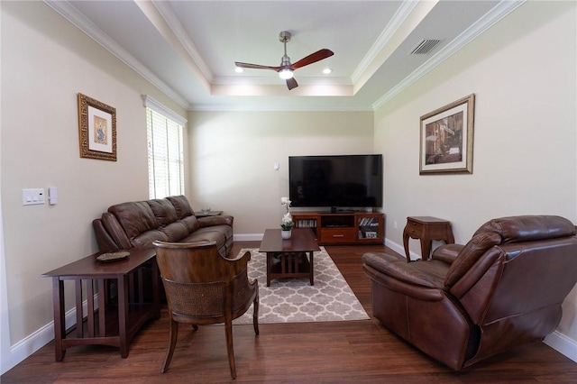 living room with ceiling fan, wood finished floors, ornamental molding, a raised ceiling, and baseboards