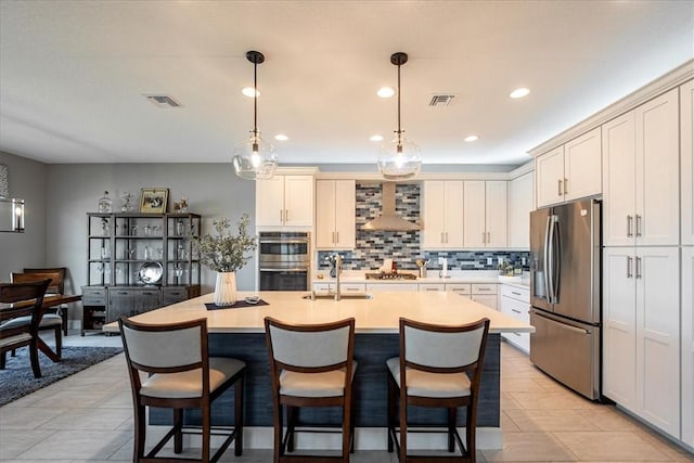 11706 SW Brighton Falls Dr, Port St Lucie, FL 34987 - kitchen with appliances with stainless steel finishes, wall chimney exhaust hood, light countertops, decorative backsplash, and a kitchen breakfast bar
