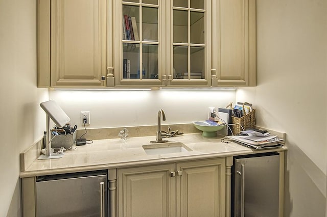 bar with sink, stainless steel fridge, and cream cabinetry