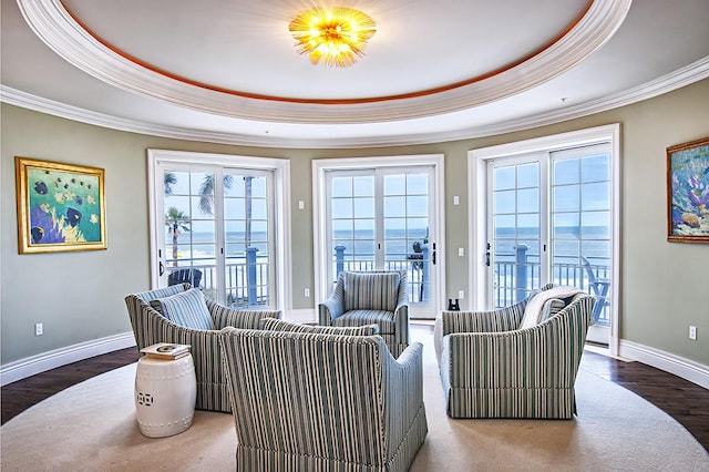 living room featuring french doors, ornamental molding, a tray ceiling, and a water view