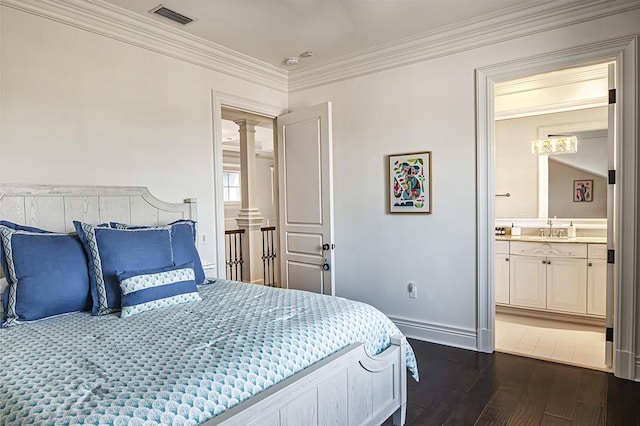 bedroom featuring sink, decorative columns, crown molding, and dark hardwood / wood-style floors