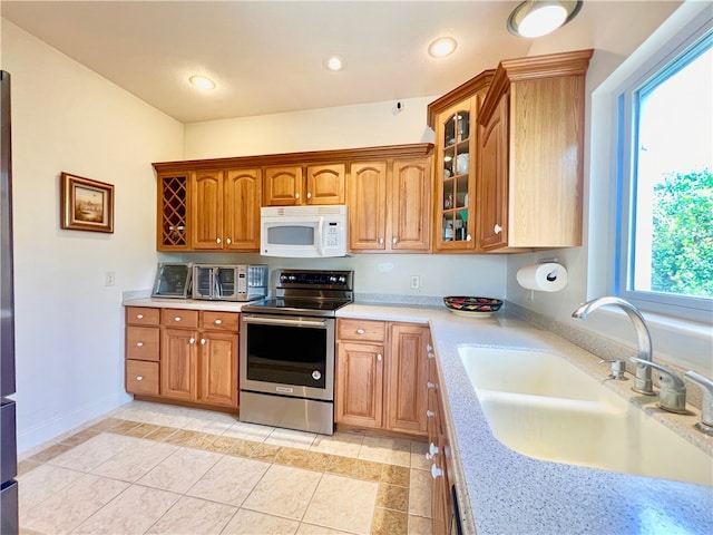 kitchen with light tile patterned floors, stainless steel electric range oven, and sink