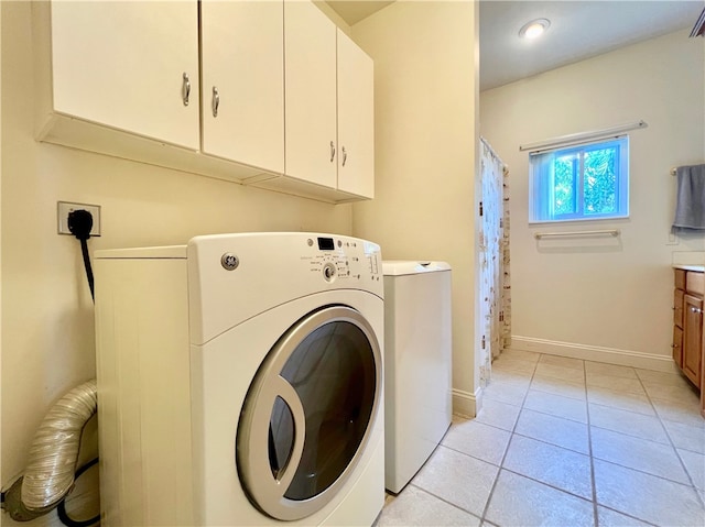 washroom featuring cabinets, light tile patterned floors, and washer and dryer