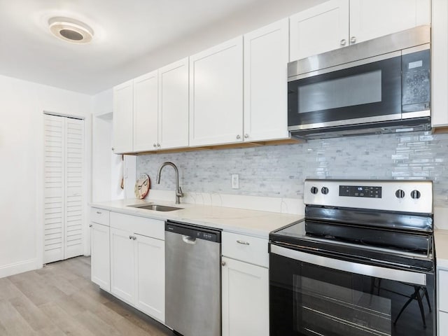 kitchen with sink, light hardwood / wood-style flooring, light stone counters, white cabinetry, and stainless steel appliances