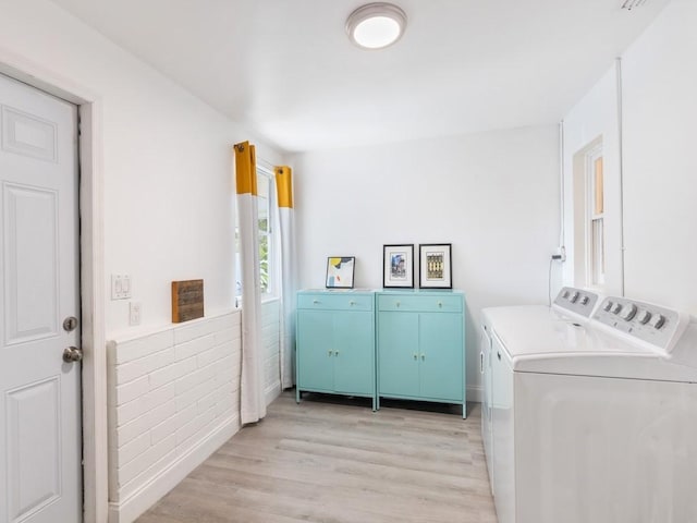 laundry room featuring cabinets, independent washer and dryer, and light hardwood / wood-style flooring